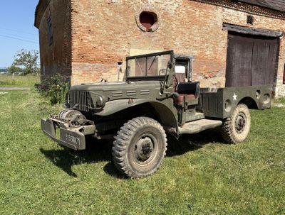 un vieux camion militaire garé devant un bâtiment en briques