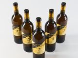 six bottles of wine are lined up in a row on a white surface
