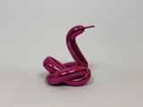 a close up of a pink sculpture of a snake on a white surface