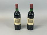 two bottles of red wine sitting next to each other on a table