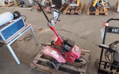 une petite tondeuse rouge posée sur une palette dans un garage