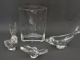 three glass birds sitting on a table next to a glass vase