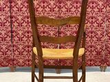 a wooden chair that is sitting in front of a red wall