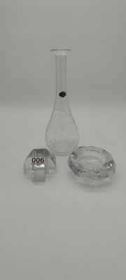 un petit vase en verre et un cendrier en verre posés sur une table blanche