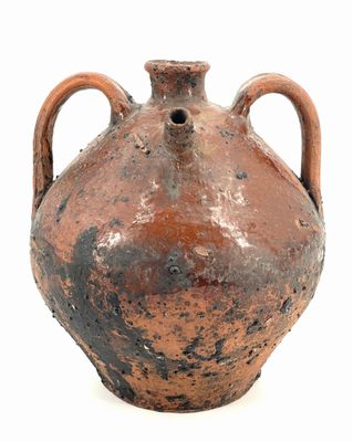 un vase marron muni de deux anses, posé sur une surface blanche