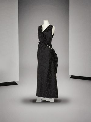 une robe noire posée sur un mannequin dans une pièce blanche