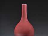 a red vase sitting on a table with a black background