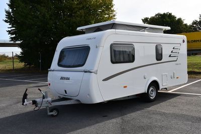 un petit camping-car blanc garé sur un parking