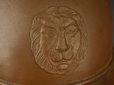 a large brown vase with a lion head on it
