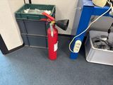 a red fire extinguisor sitting next to a trash can