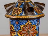 a blue and orange vase with a bird on top of it