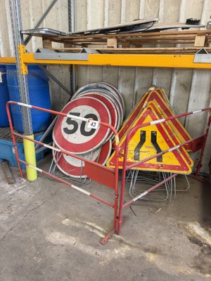 de nombreux panneaux de signalisation différents posés sur un support dans un garage