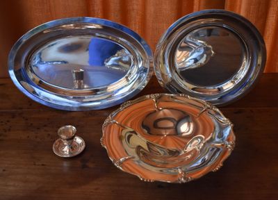 two silver dishes and a silver spoon on a wooden table