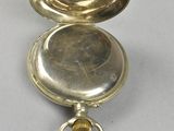 an image of a silver pocket watch with a key in it
