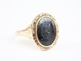 gros plan d'une bague en or contenant une pierre noire