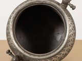 a small metal vase with a handle on a table