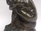 statue of a man sitting on a rock with his head in his hands