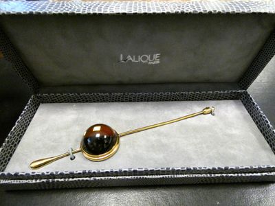 an image of a gold and black broochle in a box