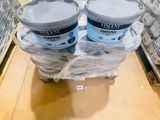three buckets of paint sitting on a pallet in a store