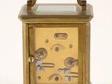 a small brass clock with a glass top on a white surface
