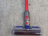 a red and silver vacuum on the floor