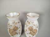 two white vases with gold designs on them