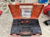 une boîte à outils contenant une perceuse et d'autres outils, posée par terre
