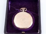 a small silver pocket watch in a purple velvet case