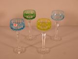 plusieurs verres à vin de couleurs différentes sont alignés sur une surface blanche