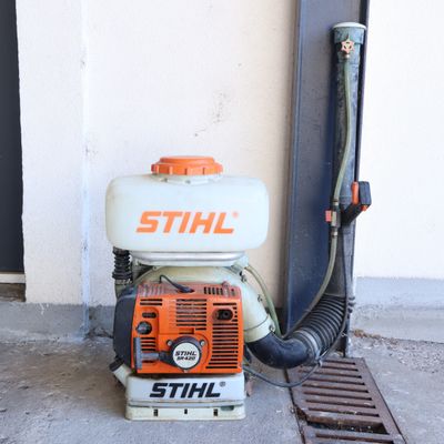 un petit ventilateur posé sur le trottoir, à côté d'un caniveau