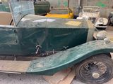 a green car parked in a garage with other cars in the background