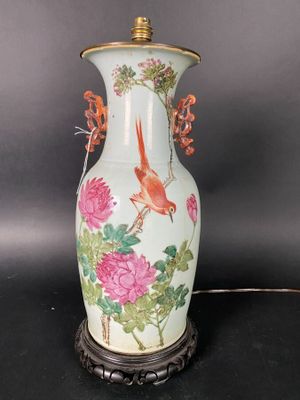 a vase with a bird and flowers on it on a table