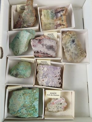 plusieurs pierres de différentes couleurs dans une boîte blanche, accompagnées d'étiquettes