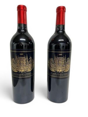 two bottles of red wine sitting next to each other on a white surface