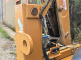 a backhoe of a tractor that is parked on the side of the road