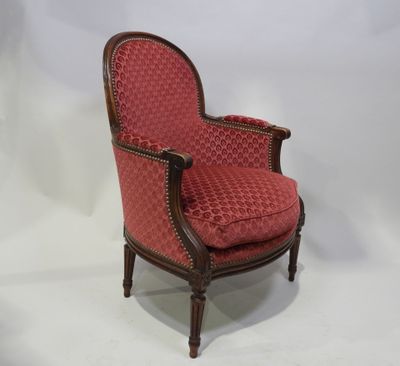 une vieille chaise dont l'assise est recouverte d'un tissu rouge sur fond blanc