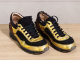 pair of black and gold sneakers on a wooden table