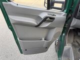 a door open of a green truck parked in a parking lot