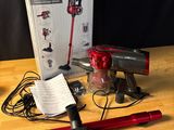 a red corded vacuum on a wooden table with a box
