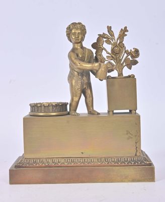 figurine en laiton représentant un garçon tenant une plante en pot, posée sur un socle