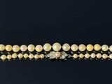 un gros plan d'un collier orné de perles et de diamants sur un fond noir