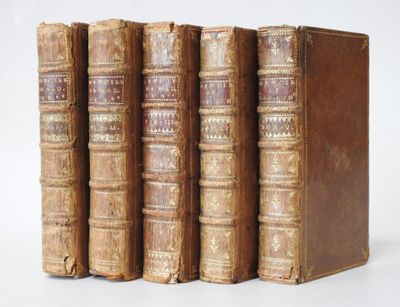 trois vieux livres posés l'un sur l'autre sur une surface blanche