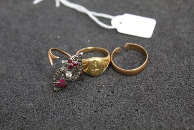 two gold rings with red stones and a tag on a black surface