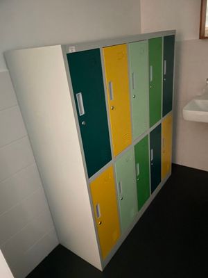 des casiers aux couleurs vives dans une salle de bains équipée d'un lavabo et d'une fenêtre