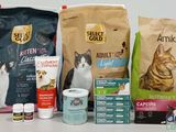 a cat sitting next to a bag of cat food and a bag of catnip