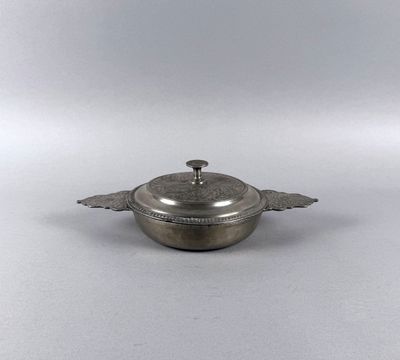 an old silver plate with a lid on a white surface