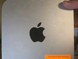 Quelqu'un tient dans ses mains un Mac mini d'Apple sur lequel est collé un autocollant.