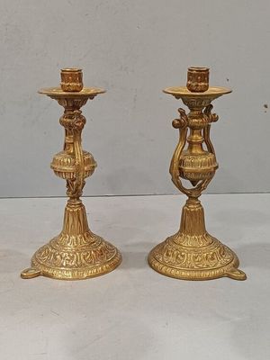 deux bougeoirs en or posés sur une table blanche
