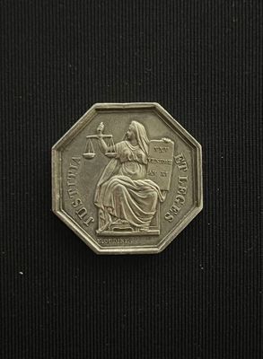 an image of a silver coin with a lady holding a scale