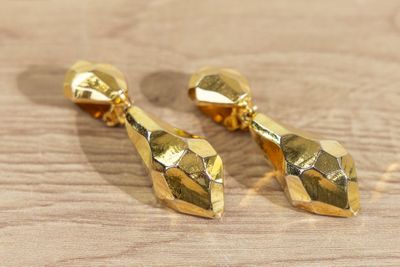 une paire de boucles d'oreilles plaquées or posées sur un support en bois